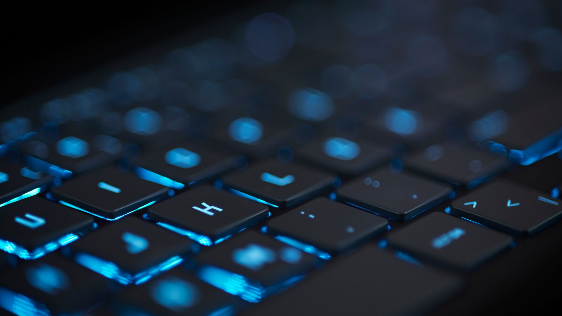 blue glowing modern keyboard with blurred bokeh background
